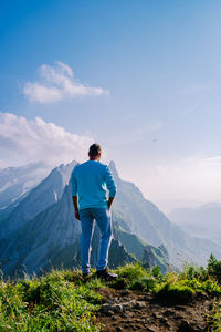 Rear view of man standing on mountain against sky