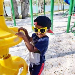 Side view of man holding sunglasses while standing at playground