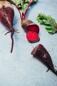 Freshly harvested whole and chopped raw organic farmer beetroot with green leaves over blue grey