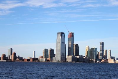 Sea by modern buildings against sky in city