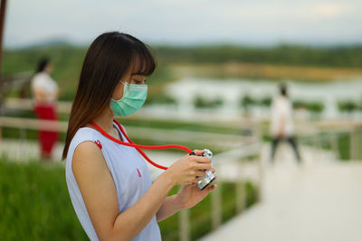 Midsection of woman holding smart phone while standing outdoors