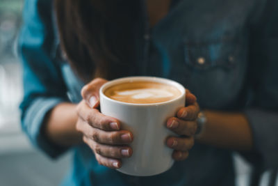 Midsection of woman holding coffee at cafe