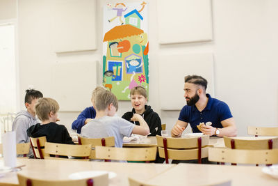 Teacher with children in classroom having lunch