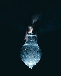 Close-up of hand holding illuminated light bulb in dark