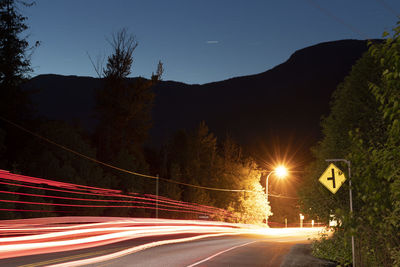 Light trails on street against sky at night