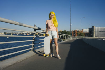 Woman standing by railing against blue sky