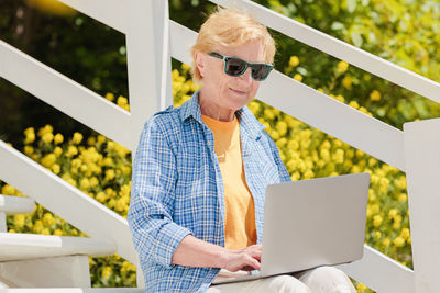 Senior authentic woman using laptop for distance learning education outdoors