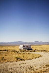 Camper van parked on field against clear sky