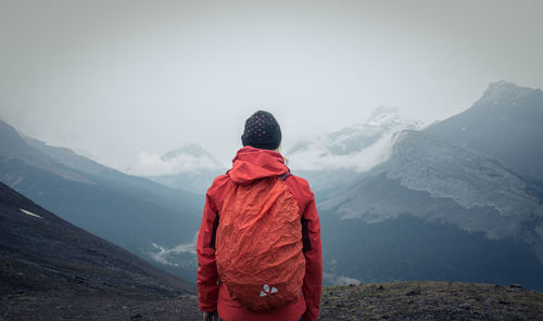 Rear view of man standing on snowcapped mountain