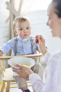 Mother feeding son at home