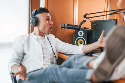 Talks and uses mic. young man is indoors in the radio studio is busy by broadcast.