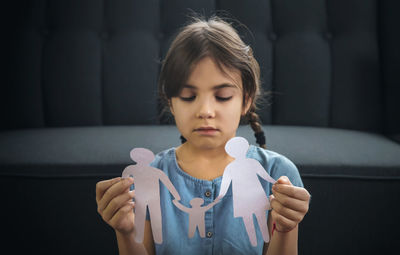 Sad girl with paper craft sitting at home