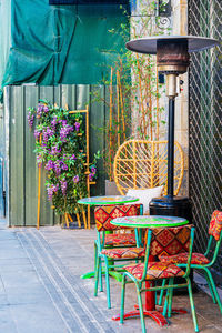 Empty chairs and table by potted plants in yard