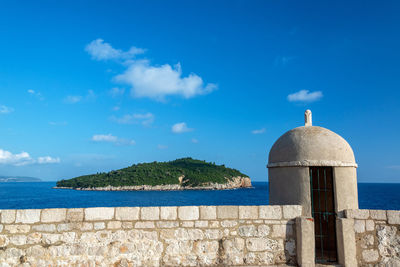 Sea by building against blue sky