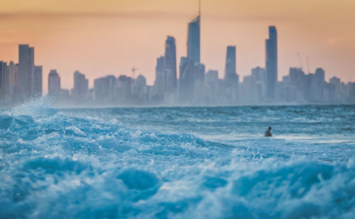 Panoramic view of sea and buildings against sky during sunset