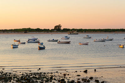 Boats moored in sea against sky during sunset