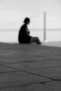 Side view of silhouette man sitting against sky