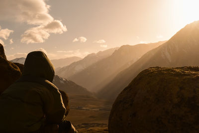 Rear view of man standing on mountain against sky