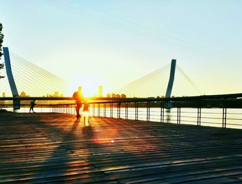 Silhouette of bridge over sea at sunset