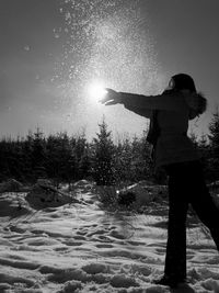 Man standing on snow covered field against sky during winter