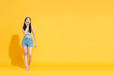 Portrait of woman standing against yellow background