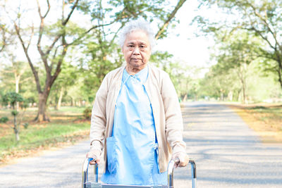 Woman with disability walker standing on road outdoors