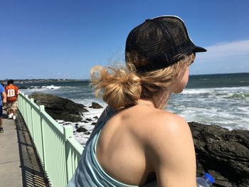 Side view of young woman standing on pier at shore