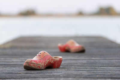 Close-up of clogs on pier over river