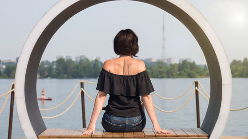 Brunette woman sits on the embankment of a european city. person