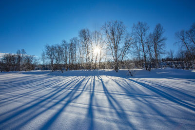 Snow covered field against clear blue sky