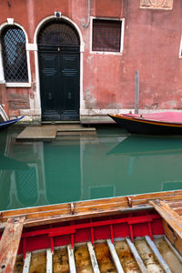 Cropped boats in canal against built structure