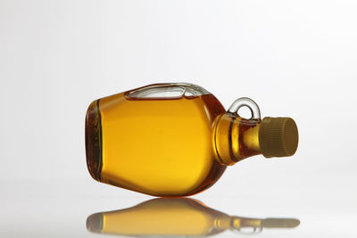 Close-up of yellow syrup in bottle against white background