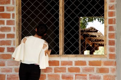 Rear view of a woman looking through window