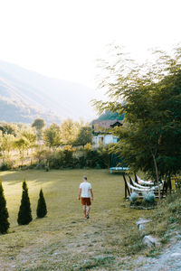 Rear view of man walking on landscape against sky