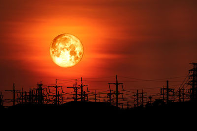 Low angle view of silhouette electricity pylon against sky during sunset