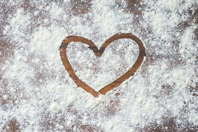 Directly above view of heart shape on flour over table