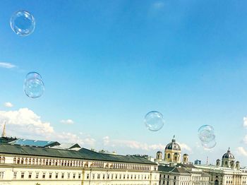 Soap bubbles with museums in background against blue sky