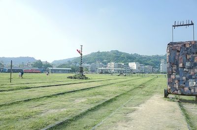 Footpath leading towards town against clear sky