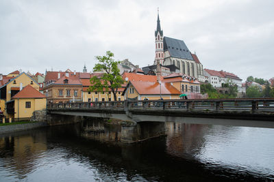 Bridge over river by buildings against sky in city