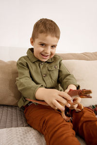 Little and cute caucasian boy playing with dinosaurs at home.