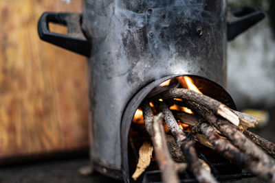 Pressure cooker kept on top of a modern chulah with wood being burnt.shalow depth of field.