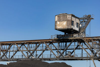 Low angle view of loader crane against clear blue sky