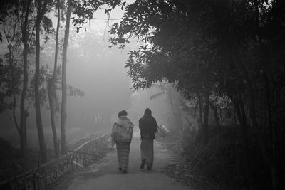 Rear view of people walking on landscape against sky