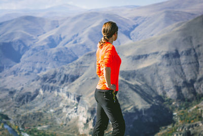 Side view of woman standing against mountains