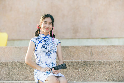 Young woman standing against wall