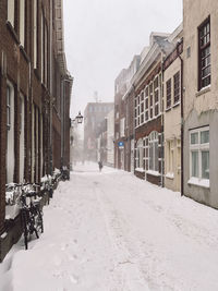 Snow covered road amidst buildings in city