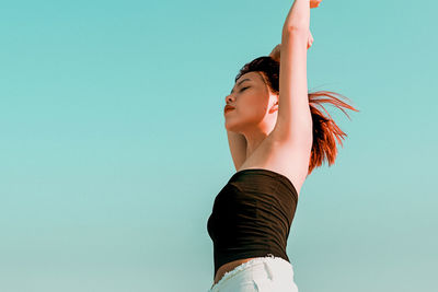 Low section of woman standing against blue wall against clear sky