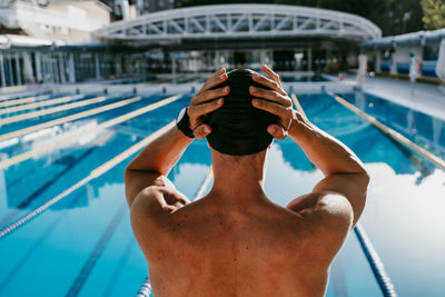Man adjusting swimming cap before diving into water during sunny day