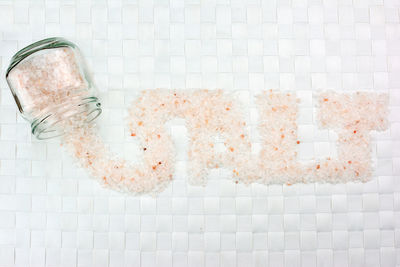 Open vase and word  salt written with pink salt on white background