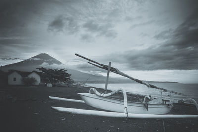 Boat moored on beach against sky